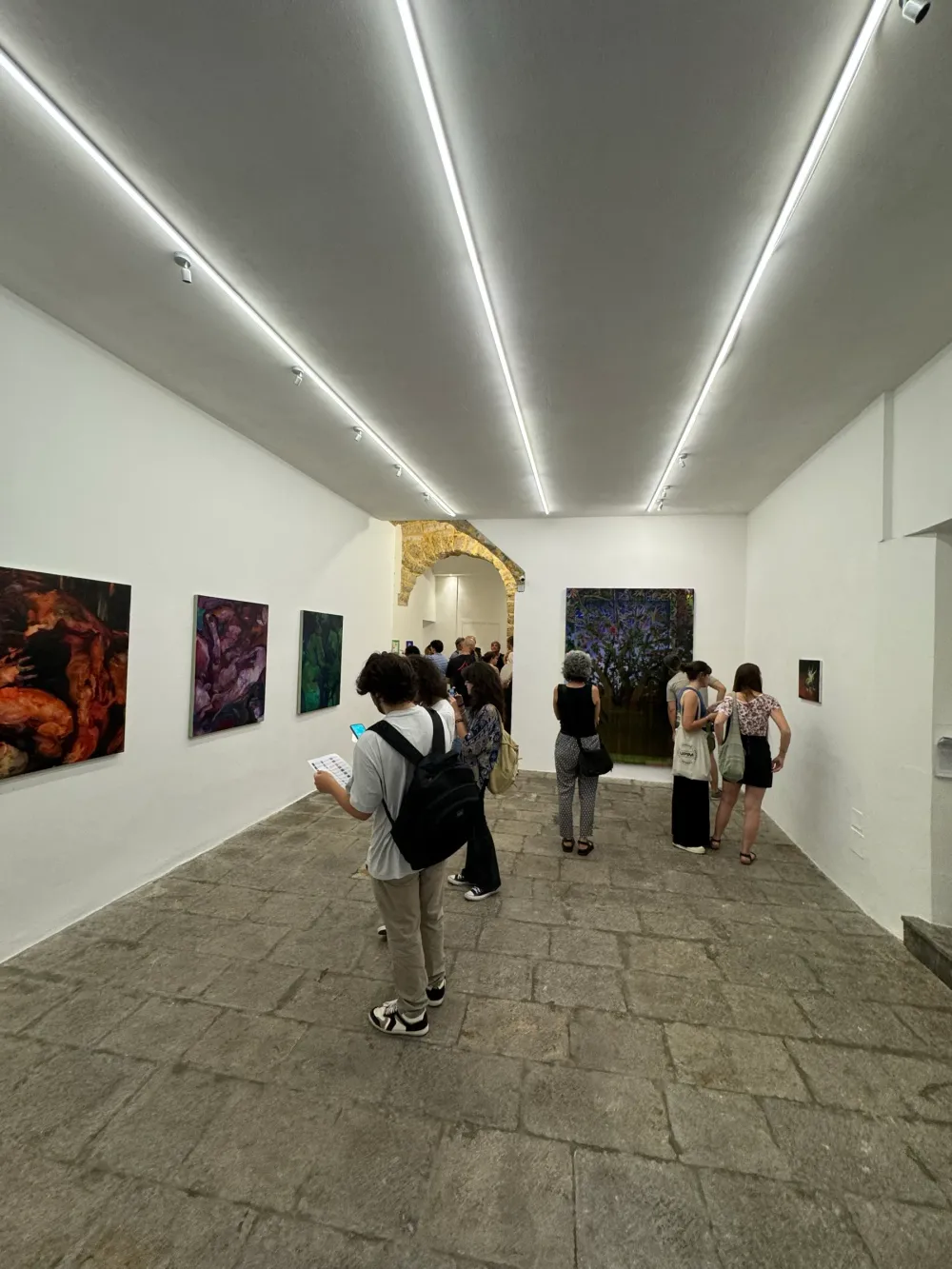 Il pubblico percorre la sala lunga con l'arco in pietra sul fondo