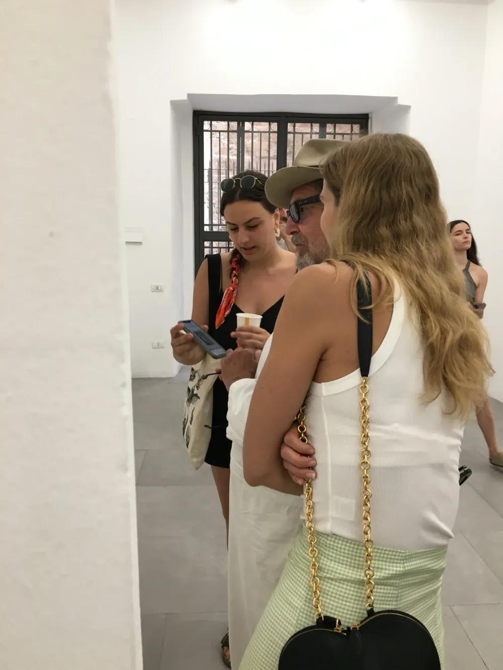 Julian Schnabel tra due visitatrici vicino a una finestra con grata